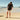 Person wearing black Archies flip flops standing on a beach 