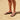 Person wearing black Archies flip flops standing on a sandy beach