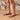 Person wearing brown Archies flip flops on a wooden floor