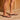 Close-up of feet wearing brown Archies flip flops on a wooden deck.