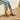 Person wearing charcoal Archies flip flops and light blue jeans on a wooden floor.