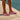 Person wearing lilac Archies flip flops standing on a wooden deck by a pool.