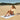 Woman wearing navy Archies flip flops sitting on a striped towel at the beach 