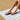Person wearing navy Archies flip flops on a striped towel at the beach