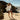 Woman wearing pink Archies flip flops standing on a rocky beach with ocean in the background