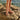 Person wearing tan Archies flip flops standing on rocks by the water