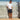 Man standing against a white picket fence wearing orange Archies flip flops, a white t-shirt and dark shorts.