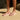 Person wearing pink Archies flip flop on a sandy beach