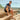 Man wearing white Archies flip flops sitting on wooden steps with a scenic view in the background